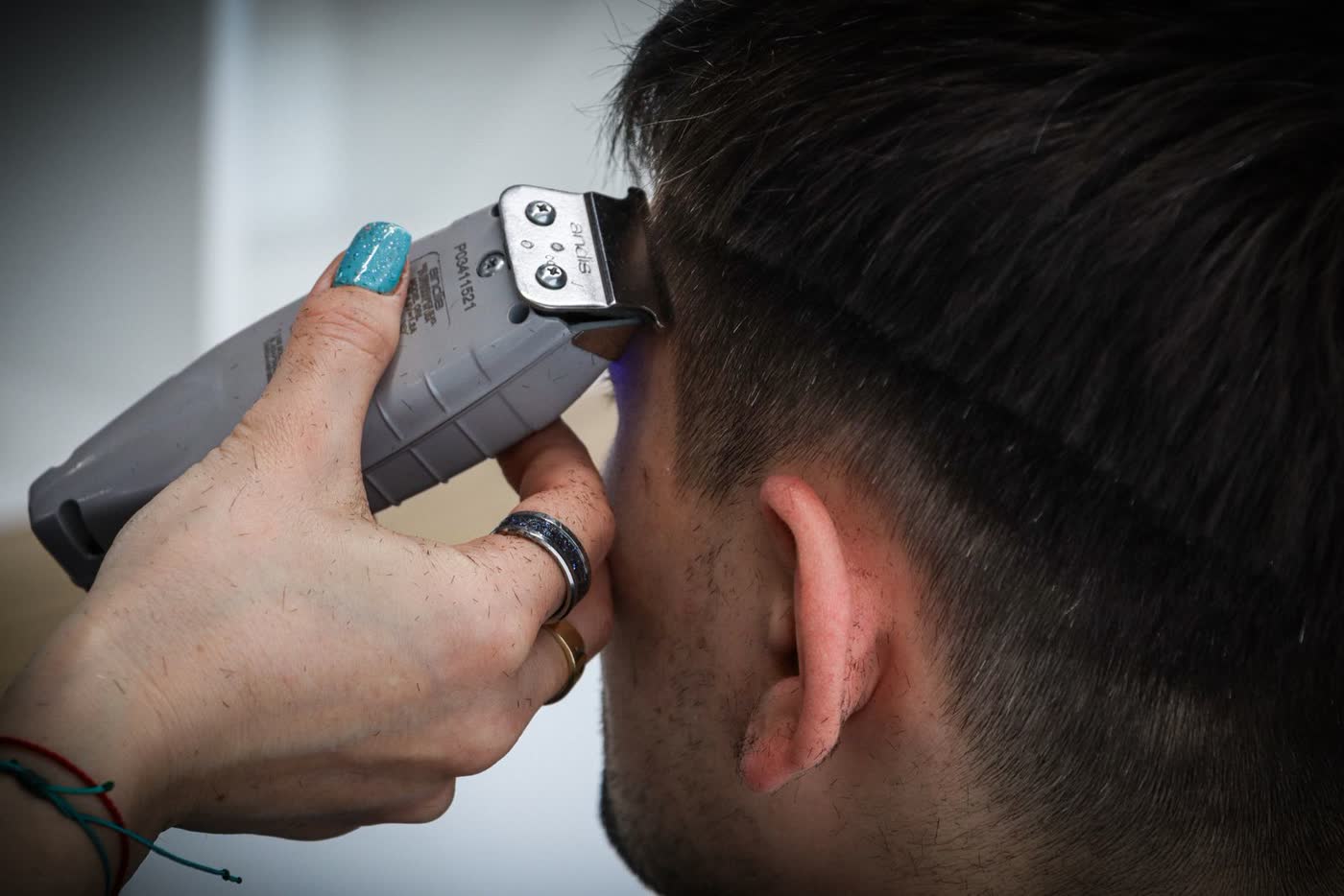 Barber fading the side of a head with clippers
