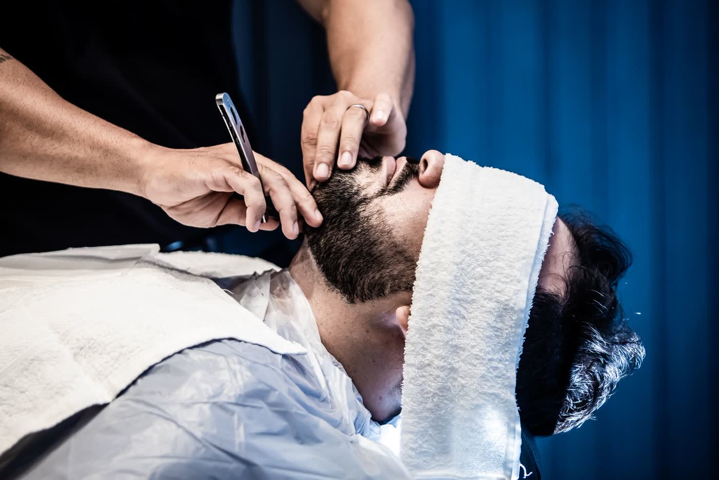 Client relaxing under a hot towel during a straight razor shave